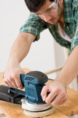 Home improvement - handyman sanding wooden floor in workshop clipart
