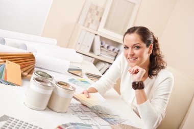 Young female interior designer at office with paint and color swatch clipart