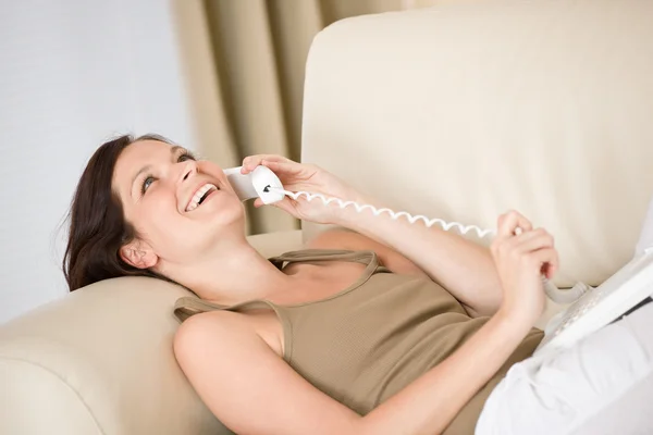 Ev telefonu: gülümseyen kadın kanepe arama üzerinde uzanmış — Stok fotoğraf