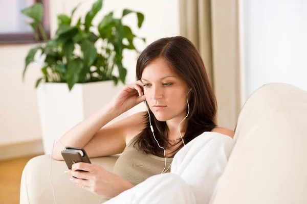 Femme tenant lecteur de musique écoutant avec des écouteurs à la maison — Photo