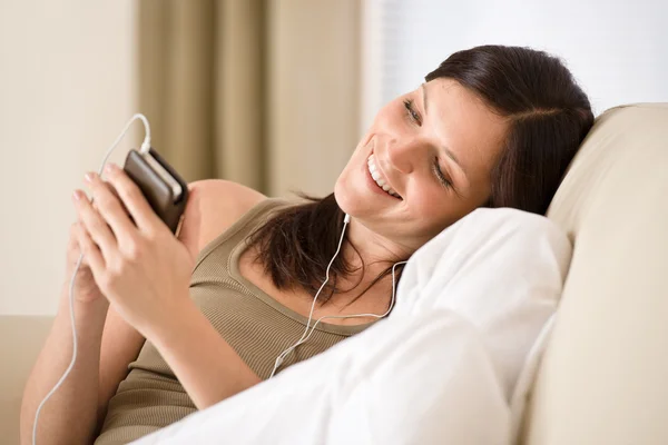Mulher segurando leitor de música ouvindo com fones de ouvido em casa — Fotografia de Stock