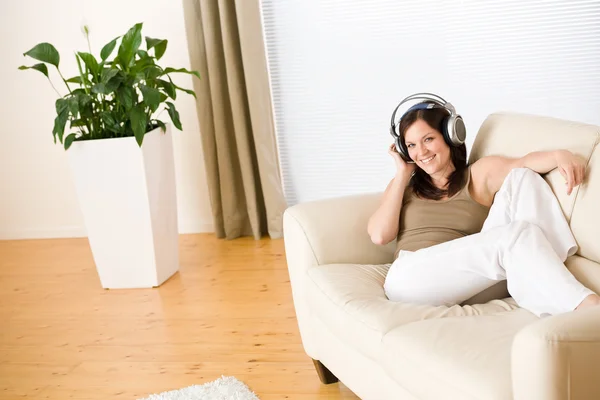 Donna con le cuffie ascoltare musica in salotto — Foto Stock