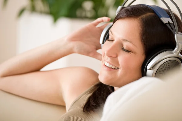 微笑的女人用耳机听音乐首页 植物在背景中 — 图库照片