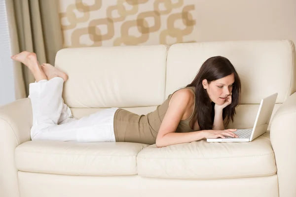 Mujer joven con portátil en el sofá de casa —  Fotos de Stock