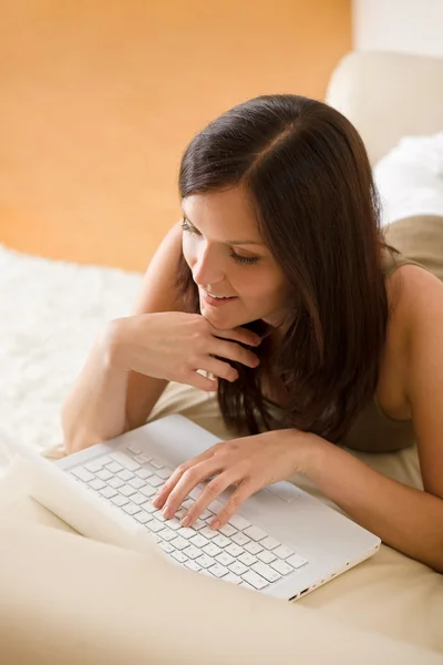 Mladá žena s laptopem doma na pohovce — Stock fotografie