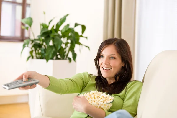Kvinnan tittar på TV med popcorn i vardagsrum — Stockfoto