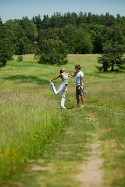 Joven hombre y mujer haciendo ejercicio en el prado de primavera —  Fotos de Stock
