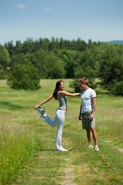 Genç erkek ve kadın bahar çayırda egzersiz — Stok fotoğraf