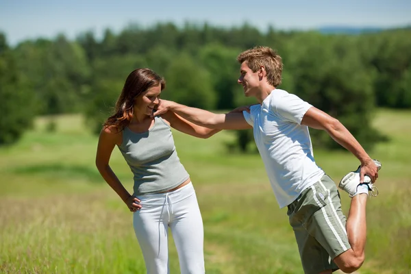 Jeune homme et femme faisant de l'exercice dans la prairie de printemps — Photo