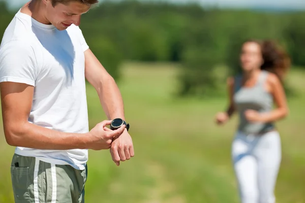 Jonge Man Met Stopwatch Tijdmeting Vrouw Achtergrond Ondiep Dof — Stockfoto