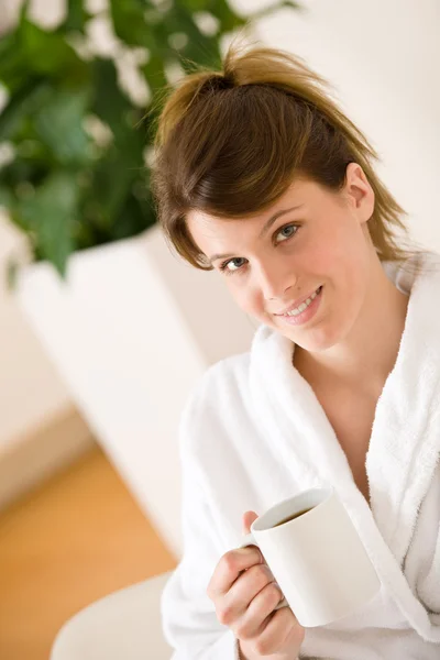 ラウンジでコーヒーの白いバスローブで若い女性 — ストック写真
