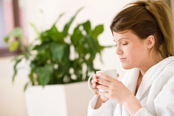 Jonge vrouw in witte badjas met koffie — Stockfoto