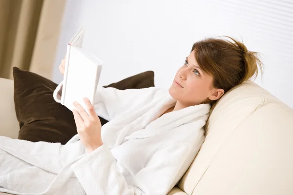 Genç Kadın Kanepe Bornoz Giymiş Dinlenme Odasında Rahatlatıcı Kitap Okumak — Stok fotoğraf