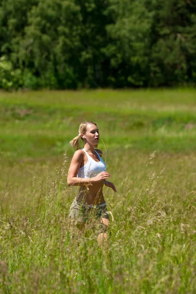 Junge Frau joggt auf einer Wiese — Stockfoto