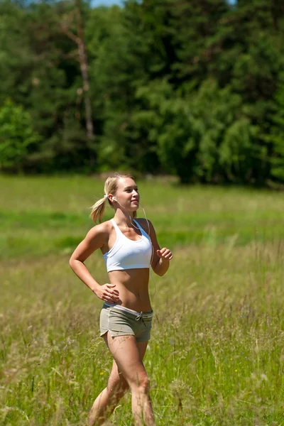 Jeune femme jogging dans une prairie — Photo