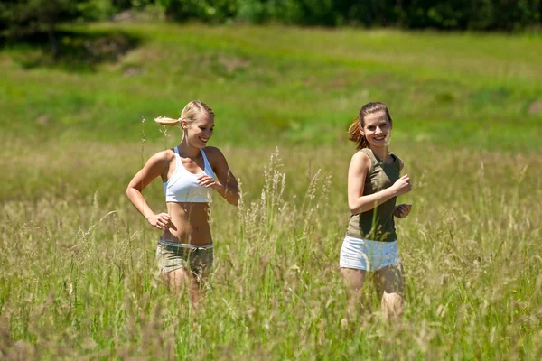 Two young woman jogging in a meadow — Stockfoto