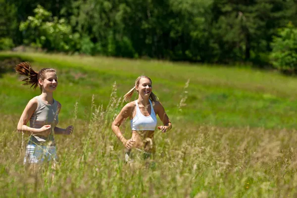 Iki genç kadın bir çayır koşu — Stok fotoğraf