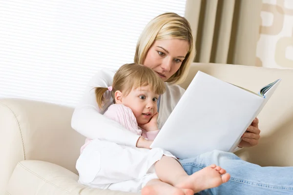 Mãe com a menina surpresa ler livro — Fotografia de Stock