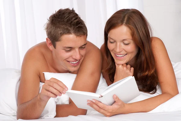 Mladý muž a žena dohromady vleže na bílé pohovce — Stock fotografie