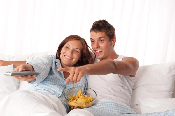Młody Mężczyzna Kobieta Leżącej Łóżku Biały Oglądanie Telewizji Jedzenie Chipsów — Zdjęcie stockowe