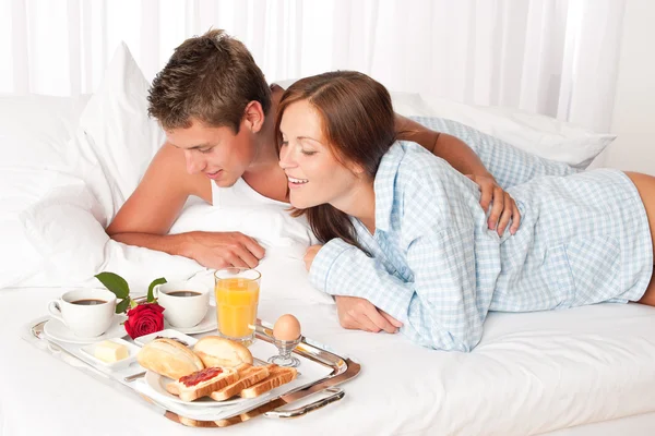 Zadowolony mężczyzna i kobieta o śniadanie w łóżku razem — Zdjęcie stockowe