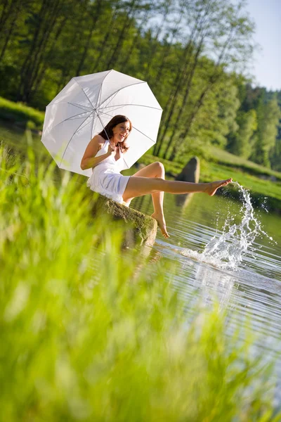 幸せなロマンチックな女性水しぶき 湖のそばに座って日傘 白いドレスを着ています — ストック写真