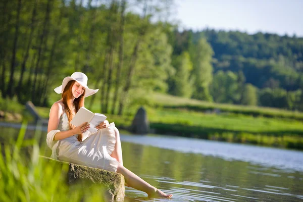 Longo cabelo vermelho mulher romântica relaxar junto ao lago com livro — Fotografia de Stock