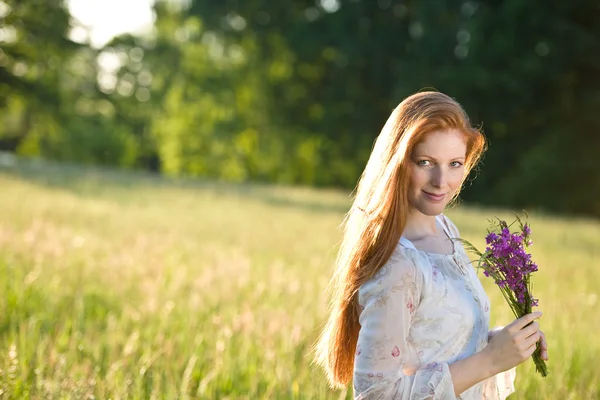Longue femme aux cheveux roux dans la prairie romantique coucher de soleil — Photo