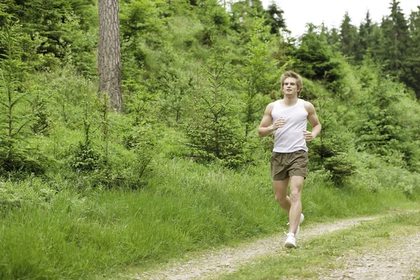 若い男が陽気な衣装で自然の中でジョギング — ストック写真
