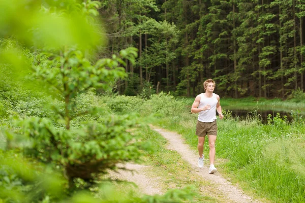 陽気な男性の陽気な衣装で湖の自然の中でジョギング — ストック写真