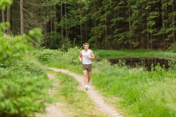 Sportive man jogging in nature by lake — Stock Photo, Image