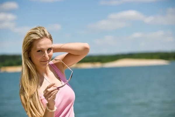 Ξανθιά γυναίκα κρατήστε γυαλιά ηλίου στην παραλία — Φωτογραφία Αρχείου