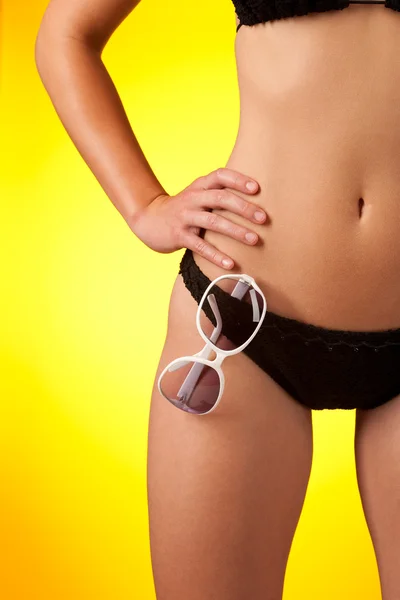 Part of female body wearing black bikini and sunglasses — Stock Photo, Image