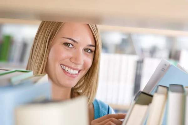 Student in library - cheerful woman look through bookshelf