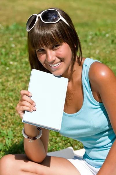 Glad ung kvinna med bok i parken — Stockfoto