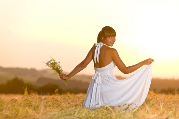 花の花束を持って日没トウモロコシ フィールド摩耗白いドレスでのロマンチックなブルネットの女性 — ストック写真