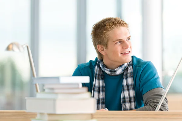 Mužský student s knihami u stolu — Stock fotografie