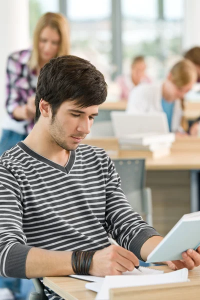 Estudiante masculino escribiendo notas en el aula — Foto de Stock