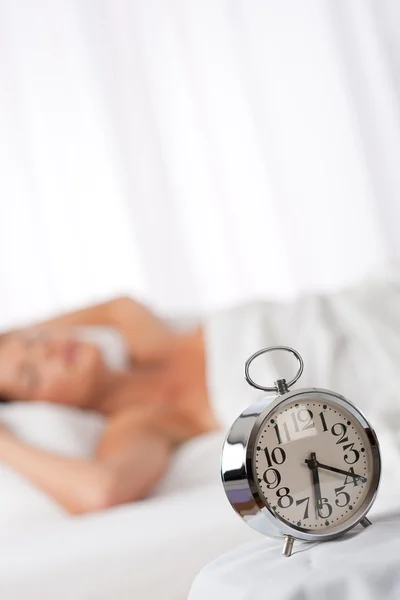 White lounge - Silver alarm clock, woman in background — Stock Photo, Image