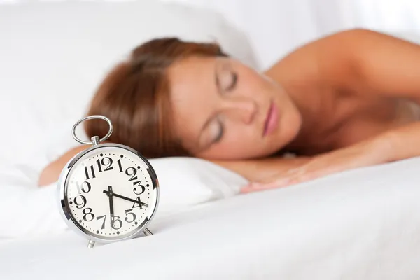 Beyaz salon - uyku ile çalar saat yatakta kadın — Stok fotoğraf