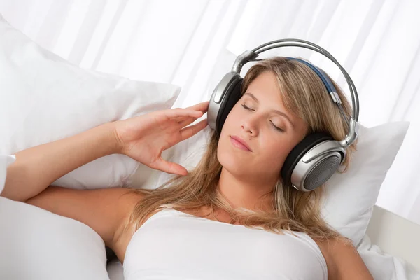 Witte lounge - blonde vrouw met koptelefoon luisteren naar muziek — Stockfoto