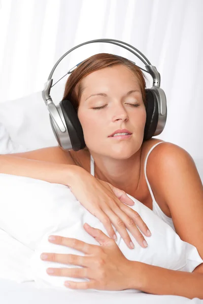 Młoda kobieta w bieli ze słuchawkami — Zdjęcie stockowe