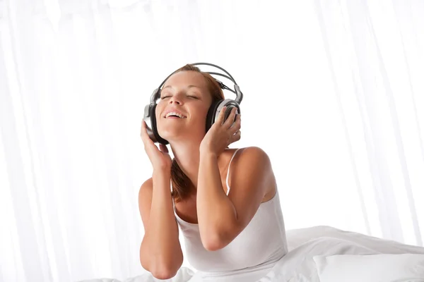 ベッドルームで音楽を聞くヘッドフォンで白の若い女性 — ストック写真
