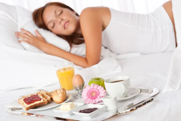 Genç bir kadın yatakta kahvaltı yapıyor. — Stok fotoğraf