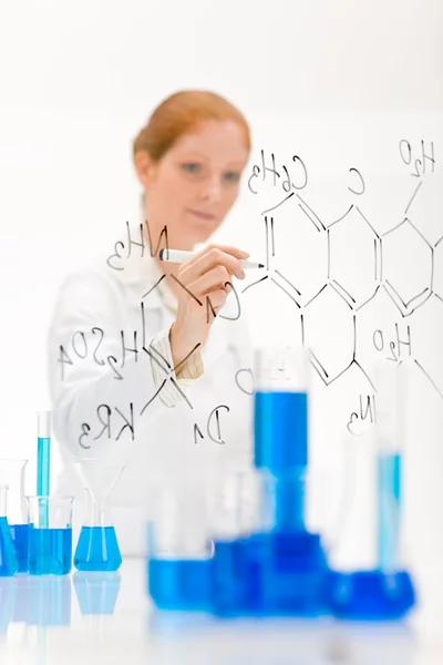 Женщина-учёный в лаборатории пишет химическую формулу — стоковое фото