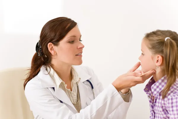 Vrouwelijke arts onderzoekende kind met zere keel — Stockfoto