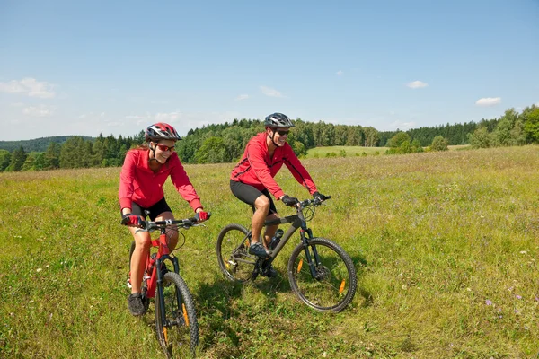 Junges Paar fährt Mountainbike auf Frühlingswiese — Stockfoto