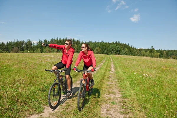 年轻夫妇骑山地自行车在春天草甸性质上阳光灿烂的日子 — 图库照片