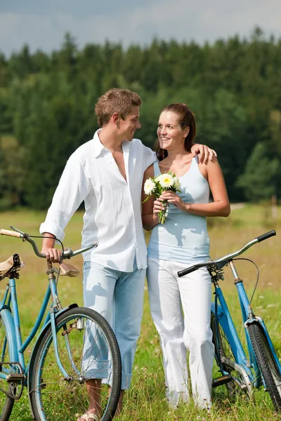 ロマンチックな若いカップルは晴れた日に牧草地で古い自転車を歩いて — ストック写真