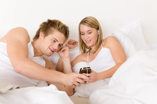 Νεαρό ζευγάρι χαλαρώσουν στο κρεβάτι να ακούσετε μουσική — Φωτογραφία Αρχείου